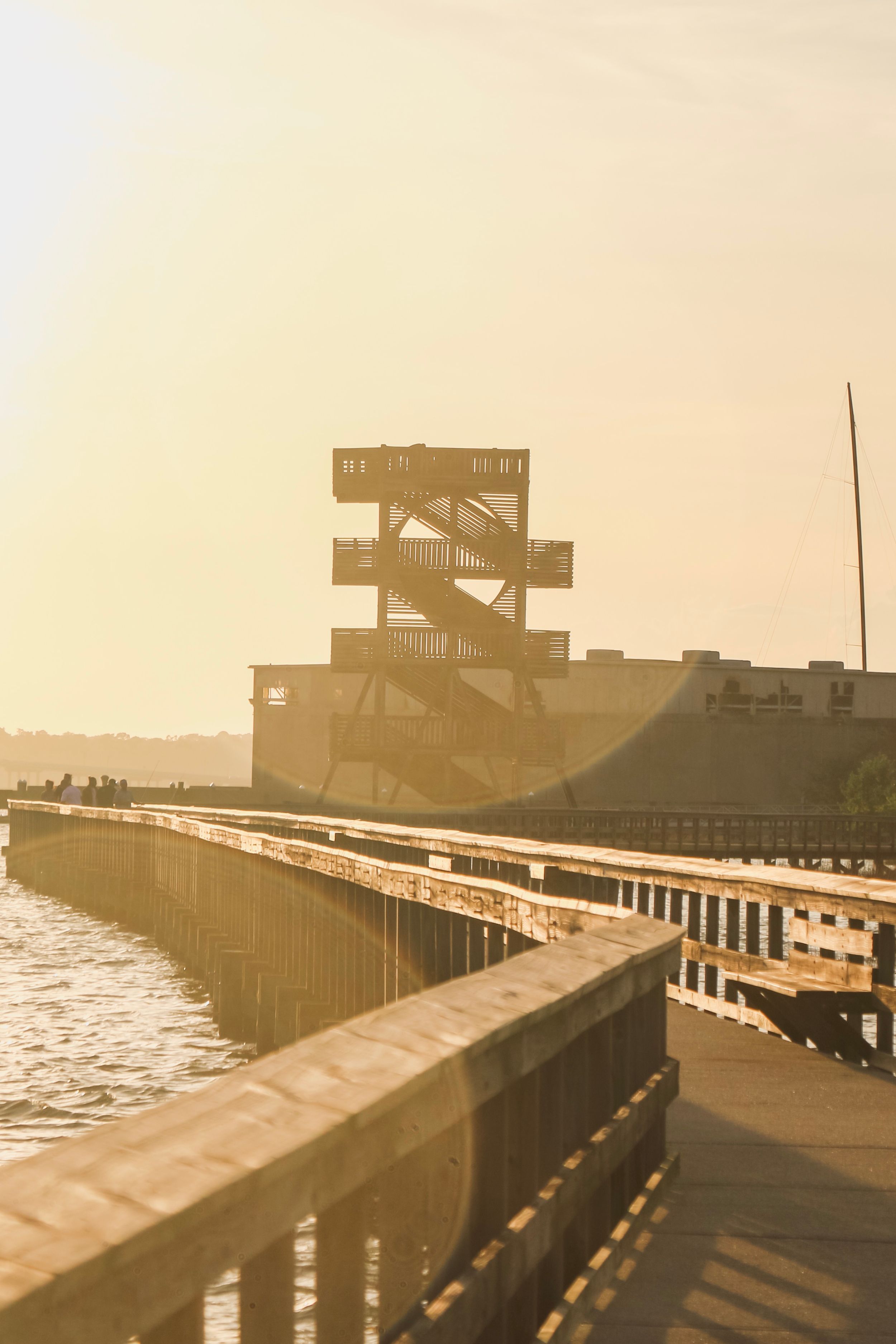 Industrial observation tower and dock silhouetted against golden sunset sky.