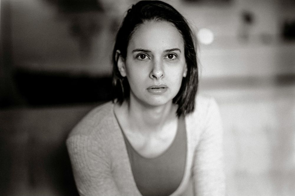 Black and white portrait of a young woman with short dark hair wearing a light sweater, gazing seriously at camera.