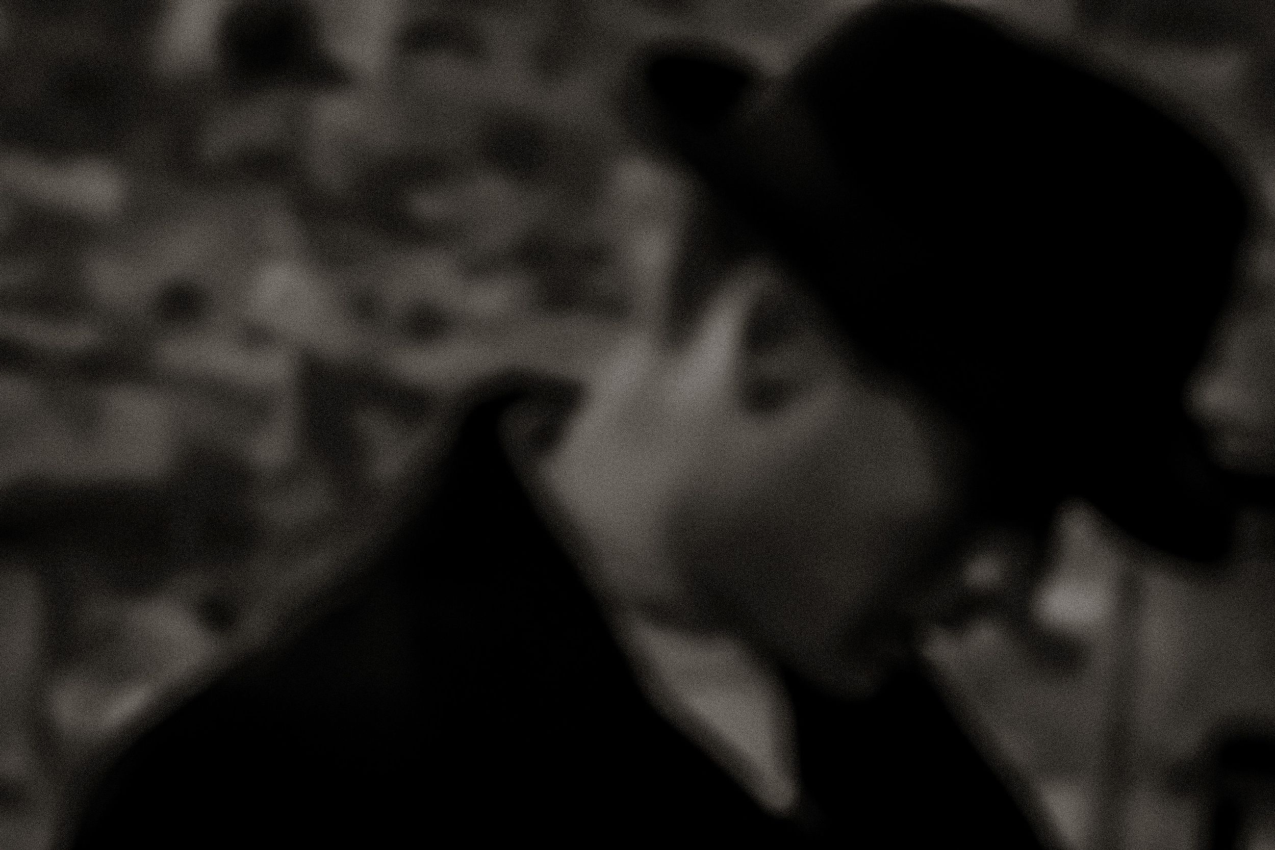 Black and white blurred portrait of a man wearing a bowler hat outdoors.