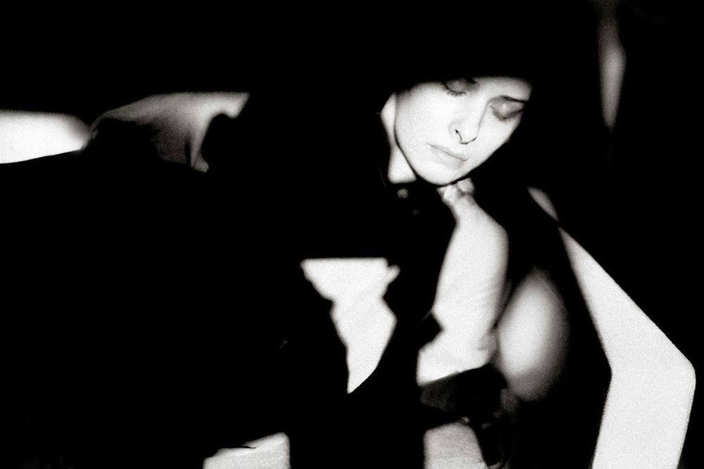 Black and white artistic portrait of a woman with closed eyes in dramatic shadows and light.