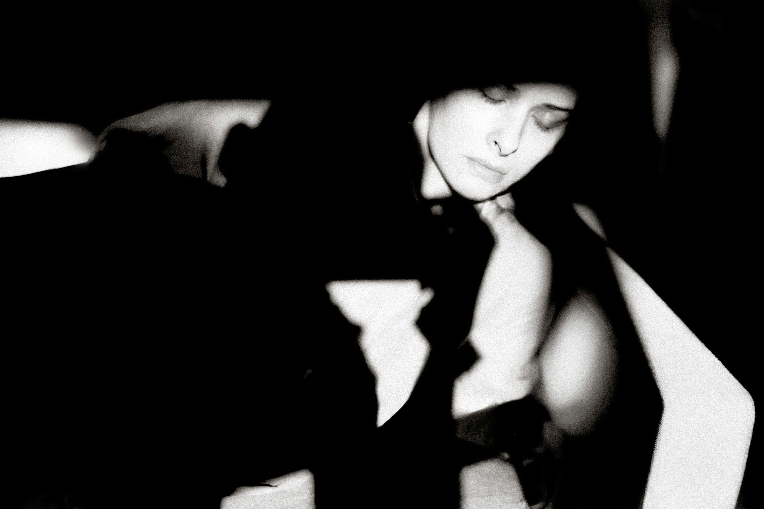 Black and white artistic portrait of a woman with closed eyes in dramatic shadows and light.