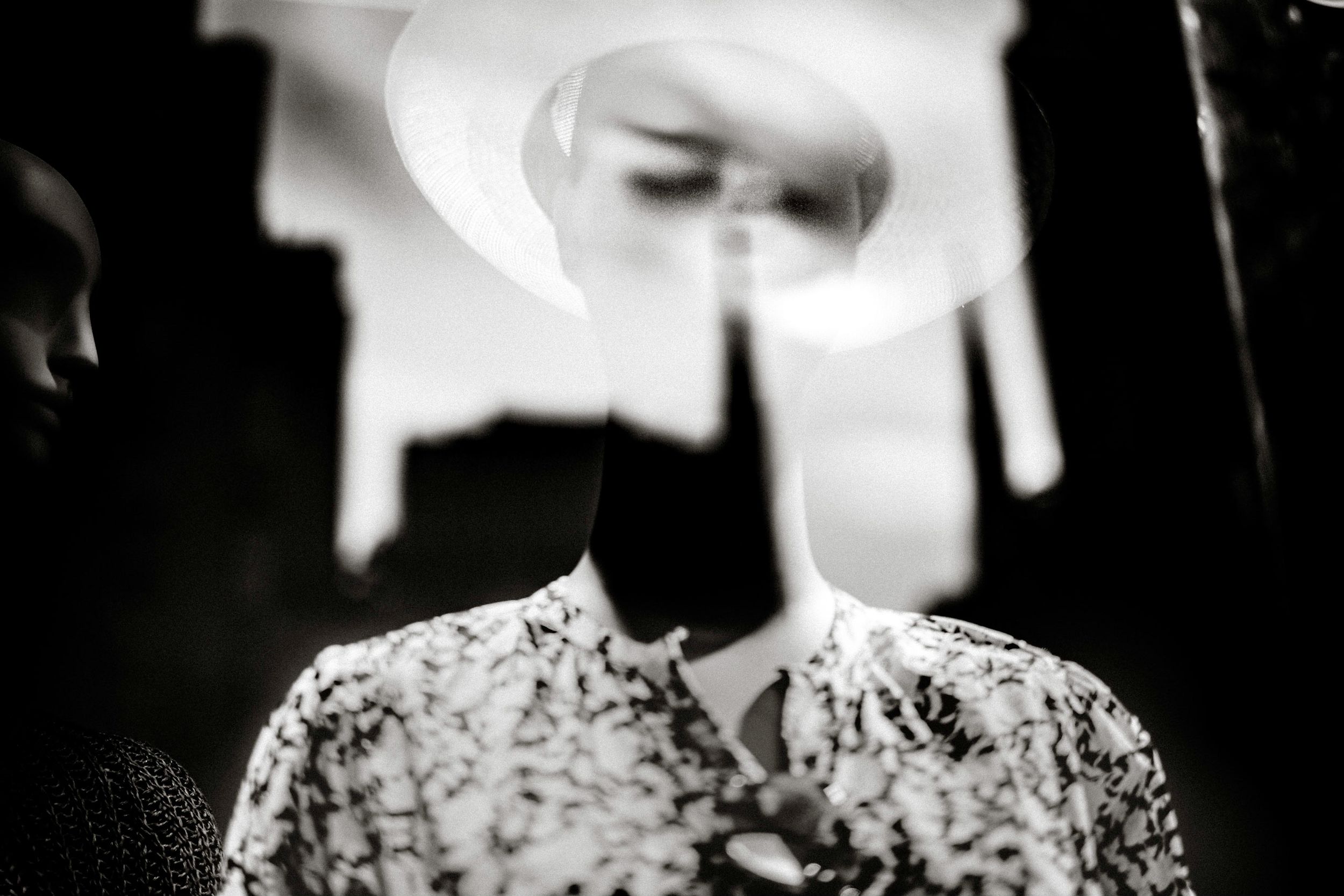 Black and white double exposure portrait of a person in floral shirt wearing a wide-brim hat, artistic surreal photography.