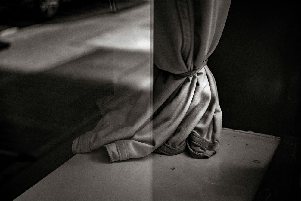 Black and white photo of draped fabric tied at the base of a column on a ledge.