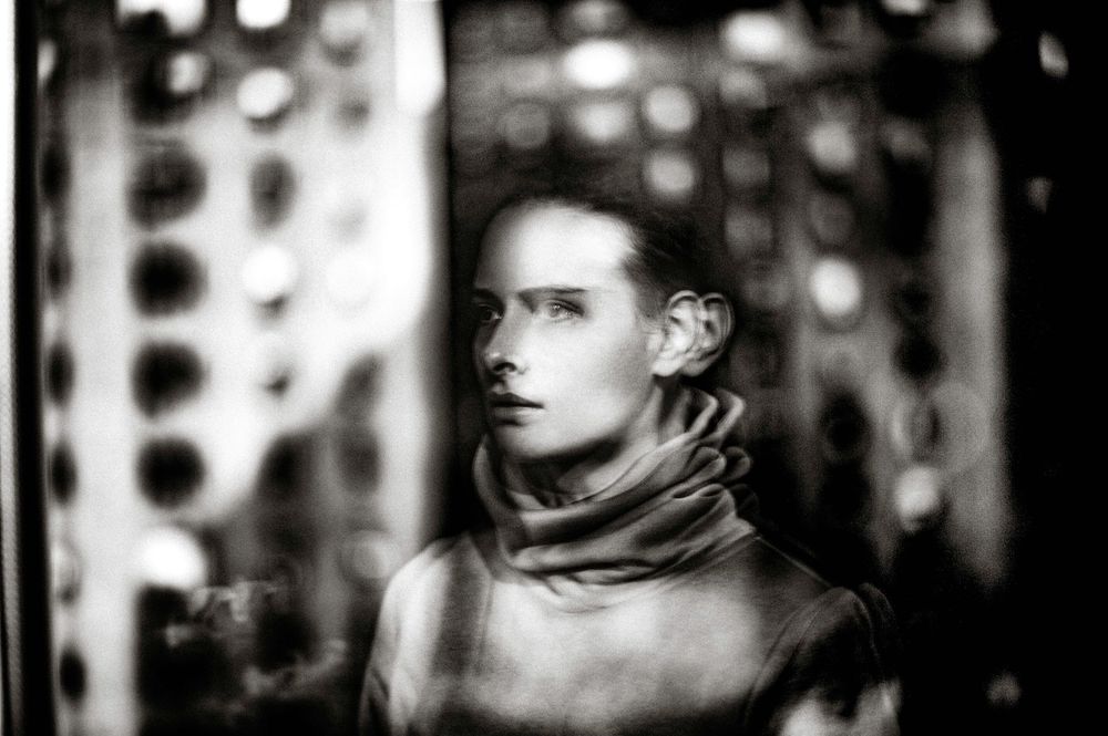 Black and white portrait of a young person wearing a turtleneck, gazing thoughtfully in dramatic studio lighting.