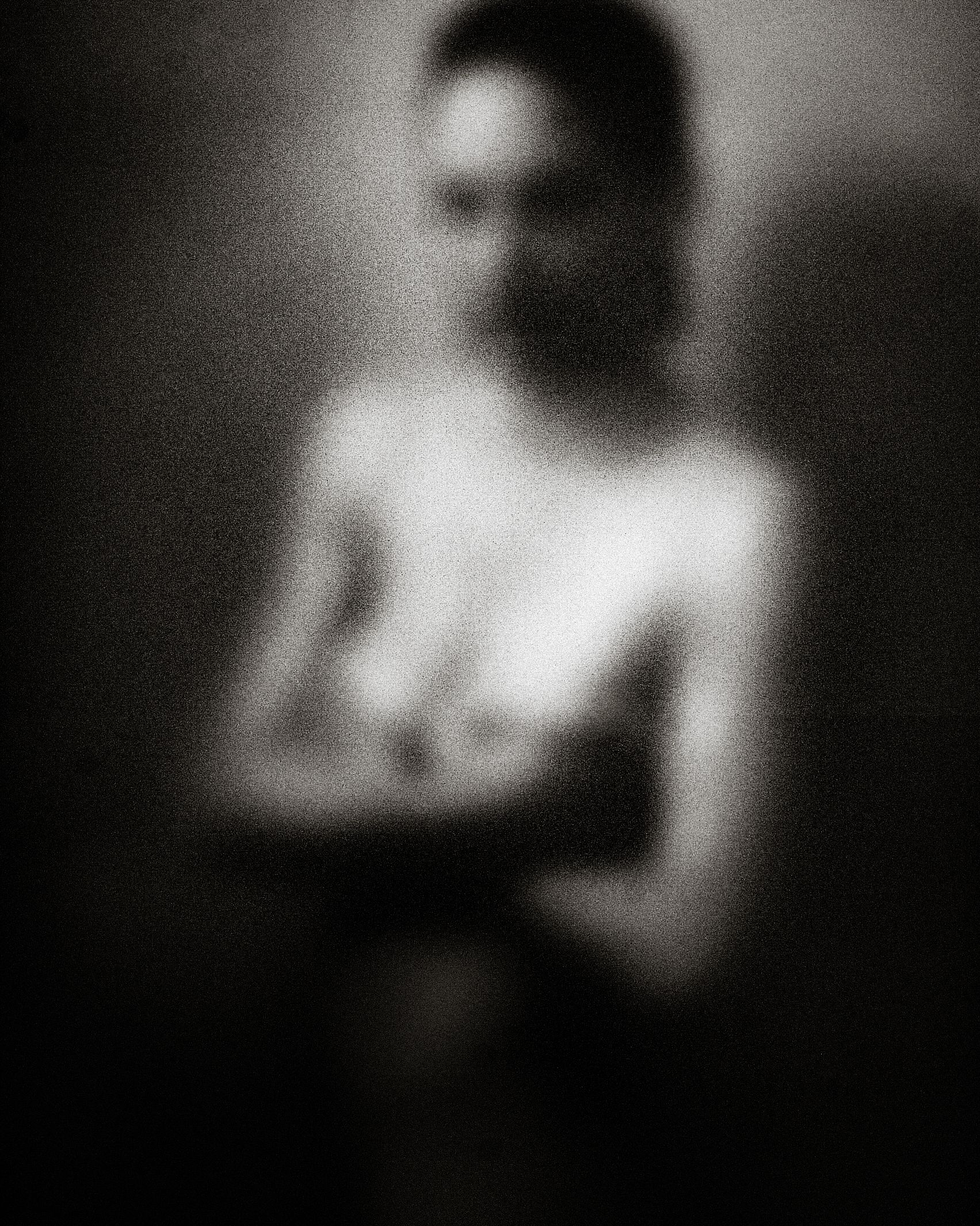 Blurred black and white artistic nude photograph with soft focus and dramatic lighting.