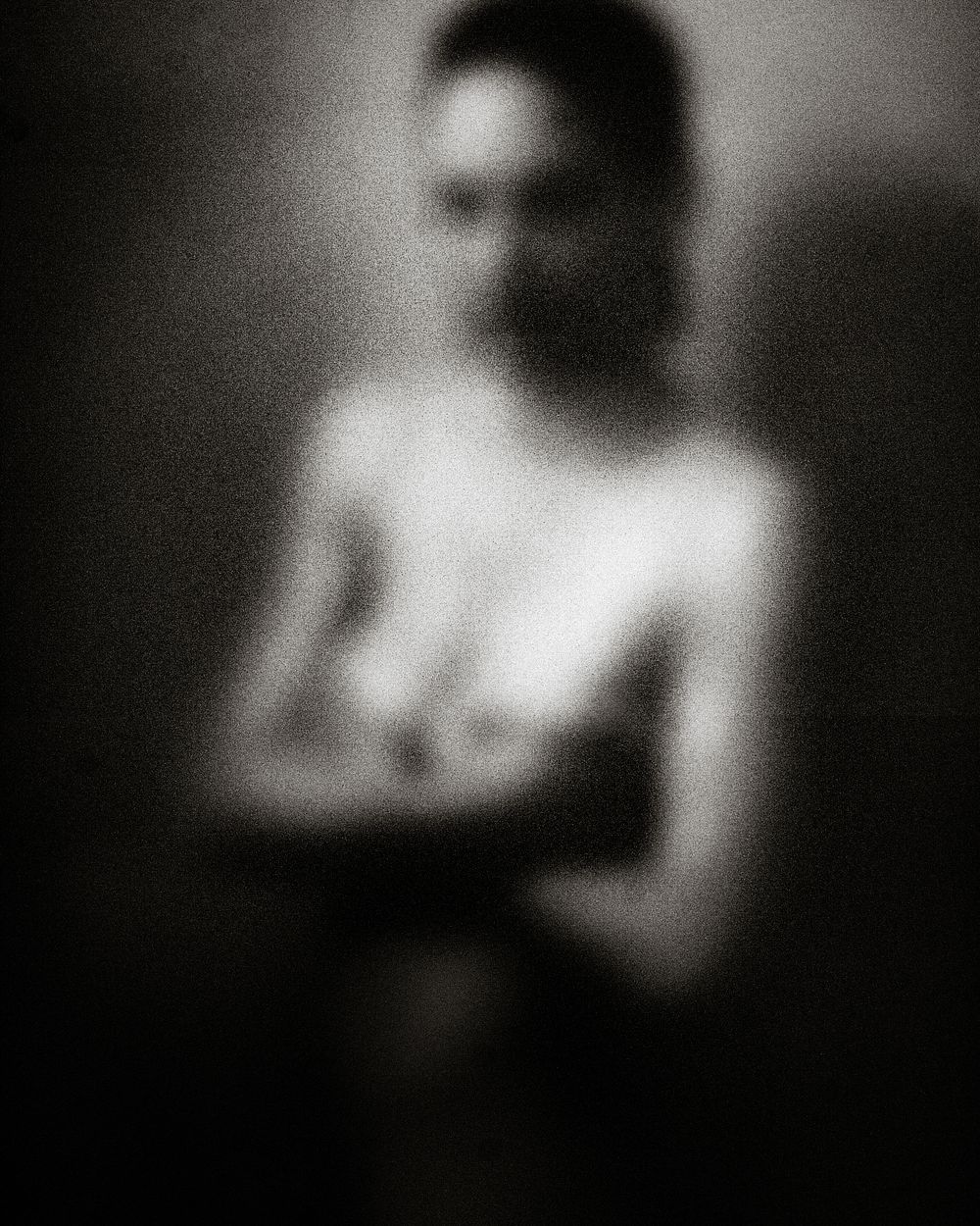 Blurred black and white artistic nude photograph with soft focus and dramatic lighting.