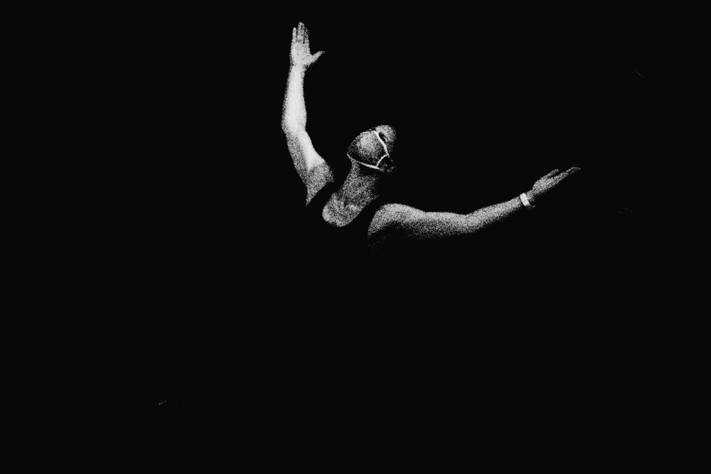 Black and white photo of a swimmer mid-dive, arms outstretched against a dark background.