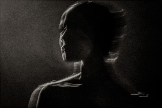 Dark artistic silhouette portrait of a person in profile, dramatic chiaroscuro lighting on black background.