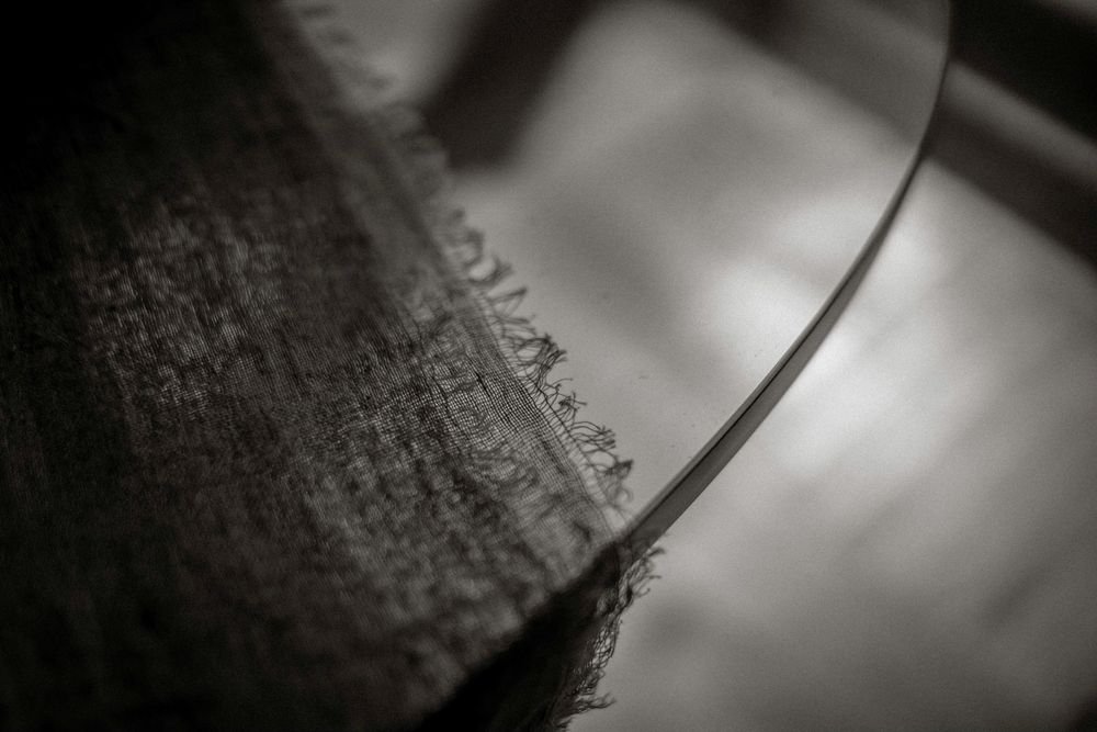 Close-up black and white macro photo of frayed fabric edge with blurred background.