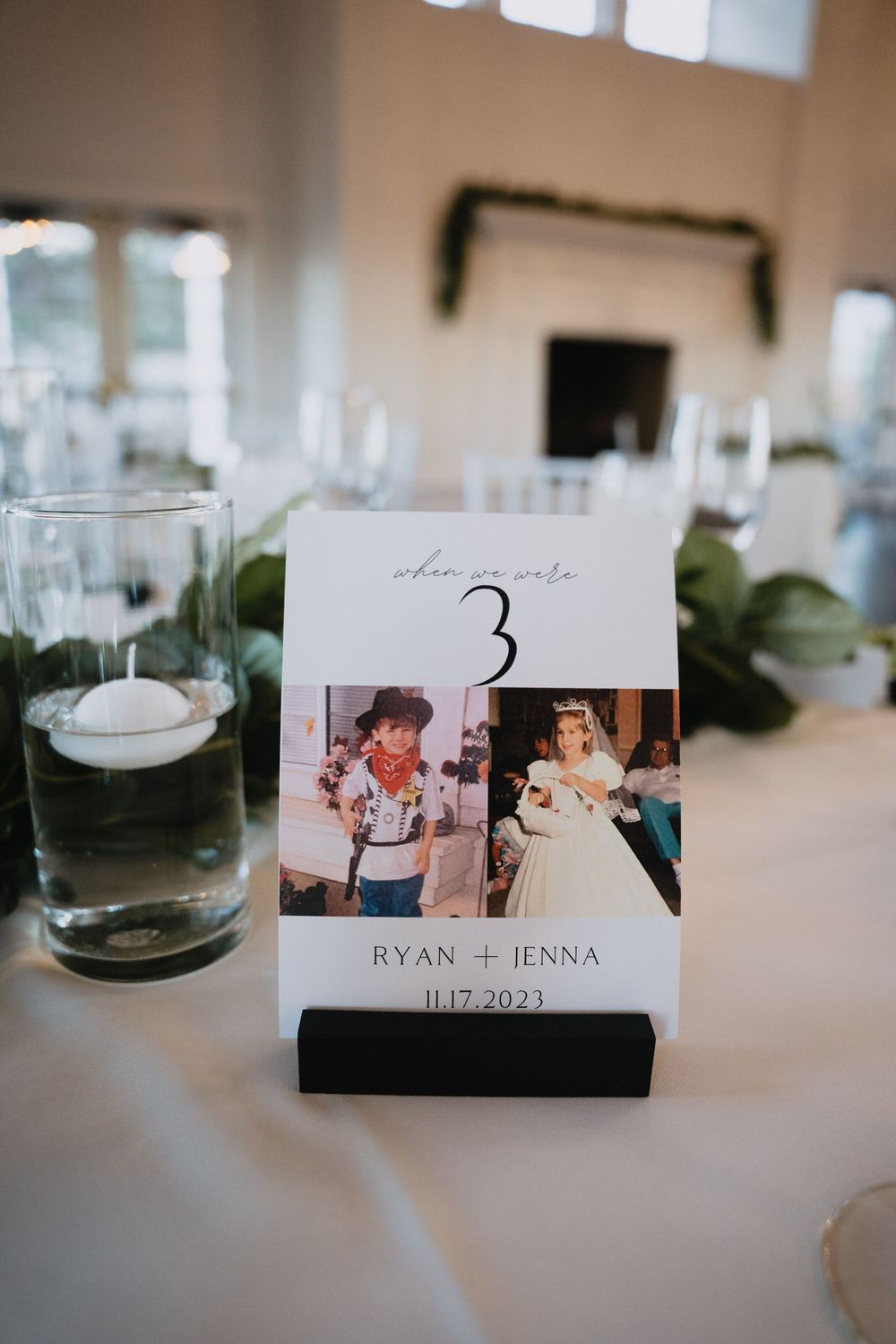 Wedding table number card for Ryan and Jenna dated 11.17.2023 featuring childhood photos beside a floating candle centerpiece.