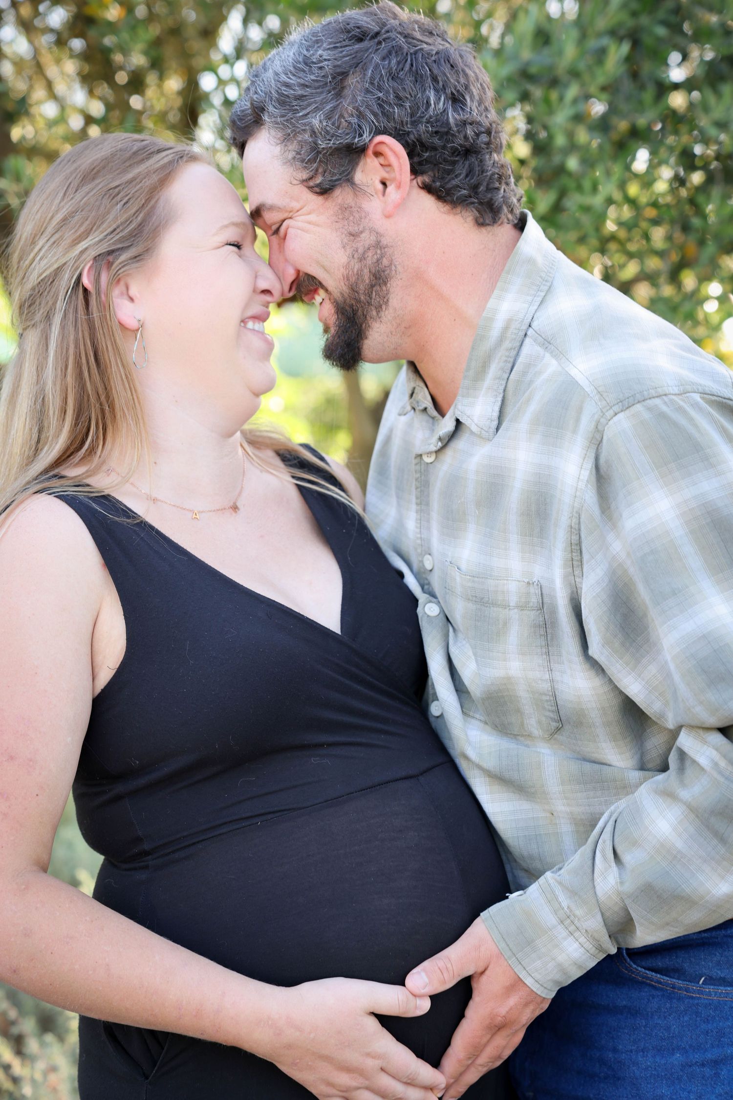 Couple touch foreheads and make a heart on growing belly during maternity portraits in Paso Robles California