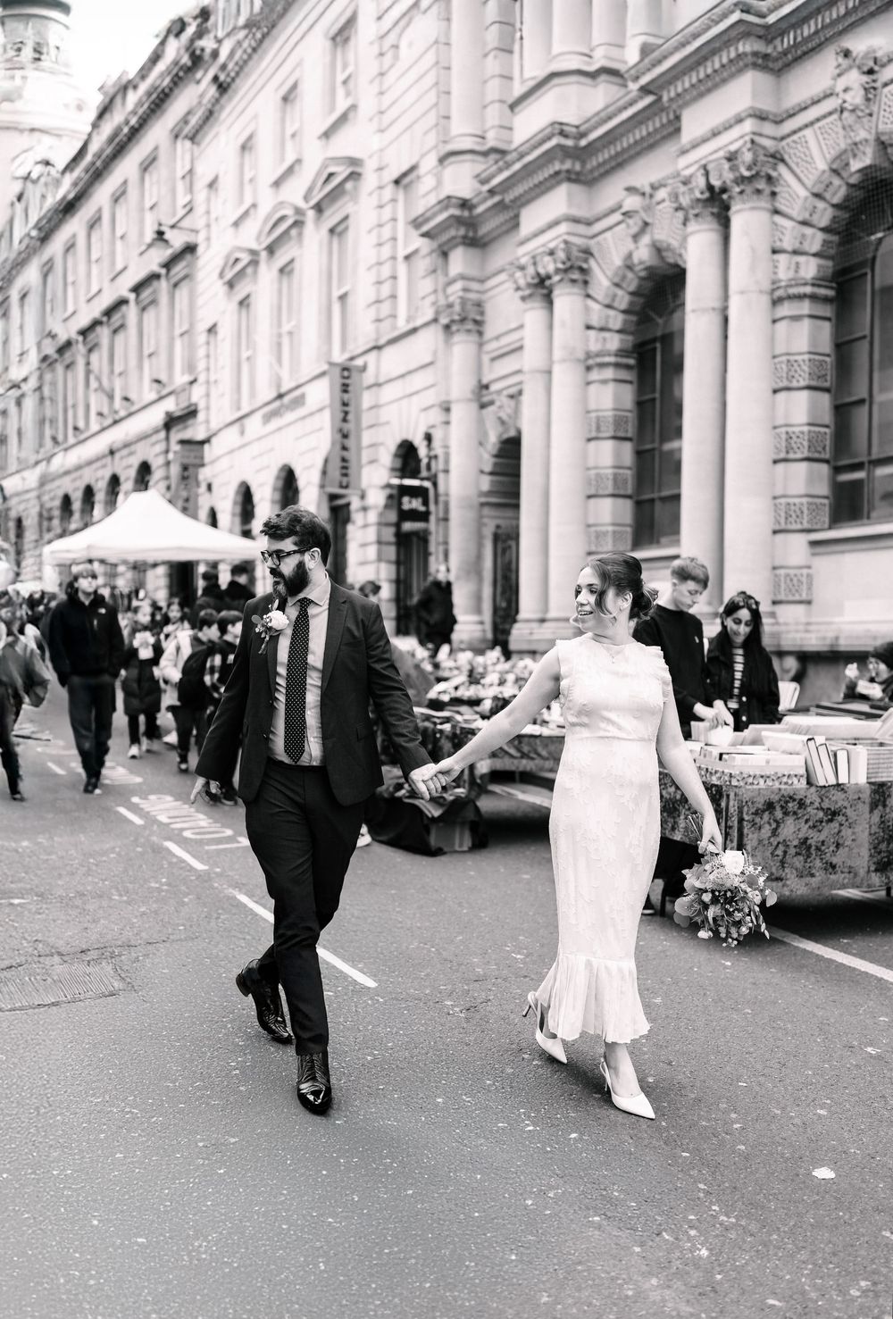 Bride and groom walking hand in hand along Corn Street after their Bristol Registry Office wedding.