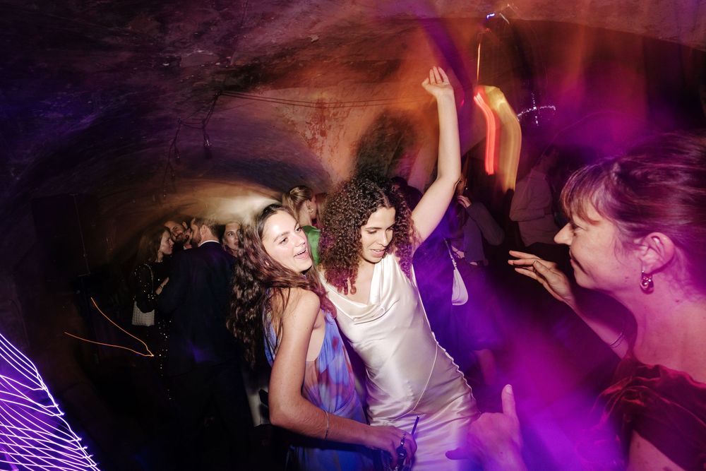 Women dancing energetically at a vibrant The Mount without wedding party with colourful purple and pink lights.