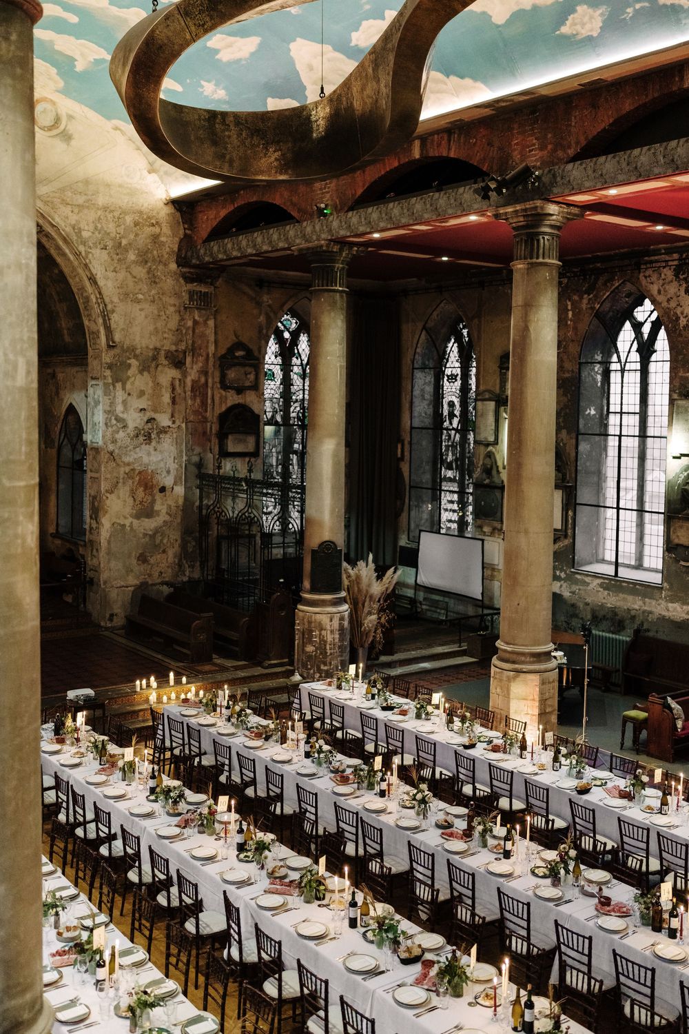 Elegant wedding reception in a The Mount without Bristol venue with long decorated tables, candles, and Gothic arched windows.