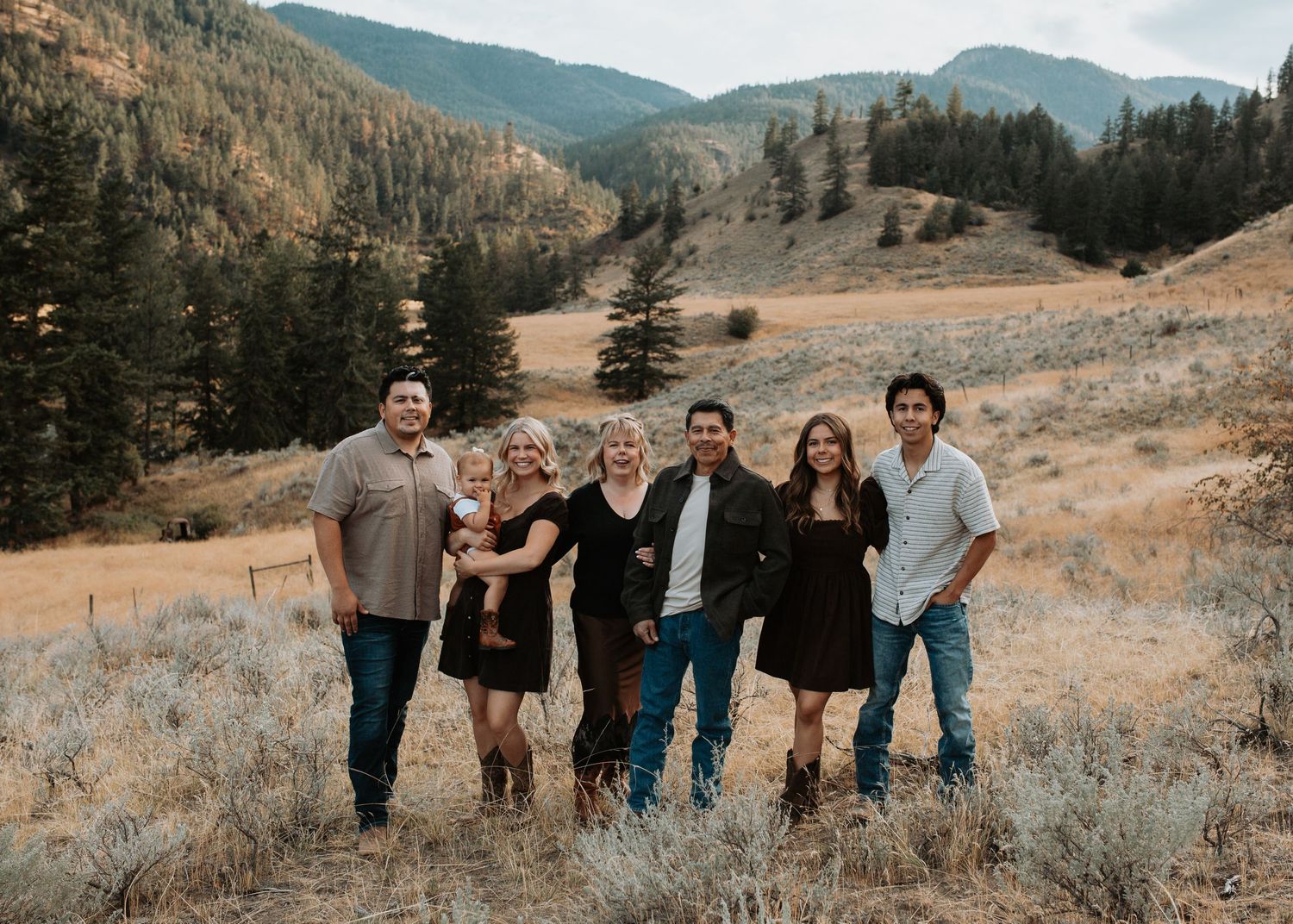 Fall family portrait surrounded by dry golden grasses and mountain scenery in the South Okanagan.