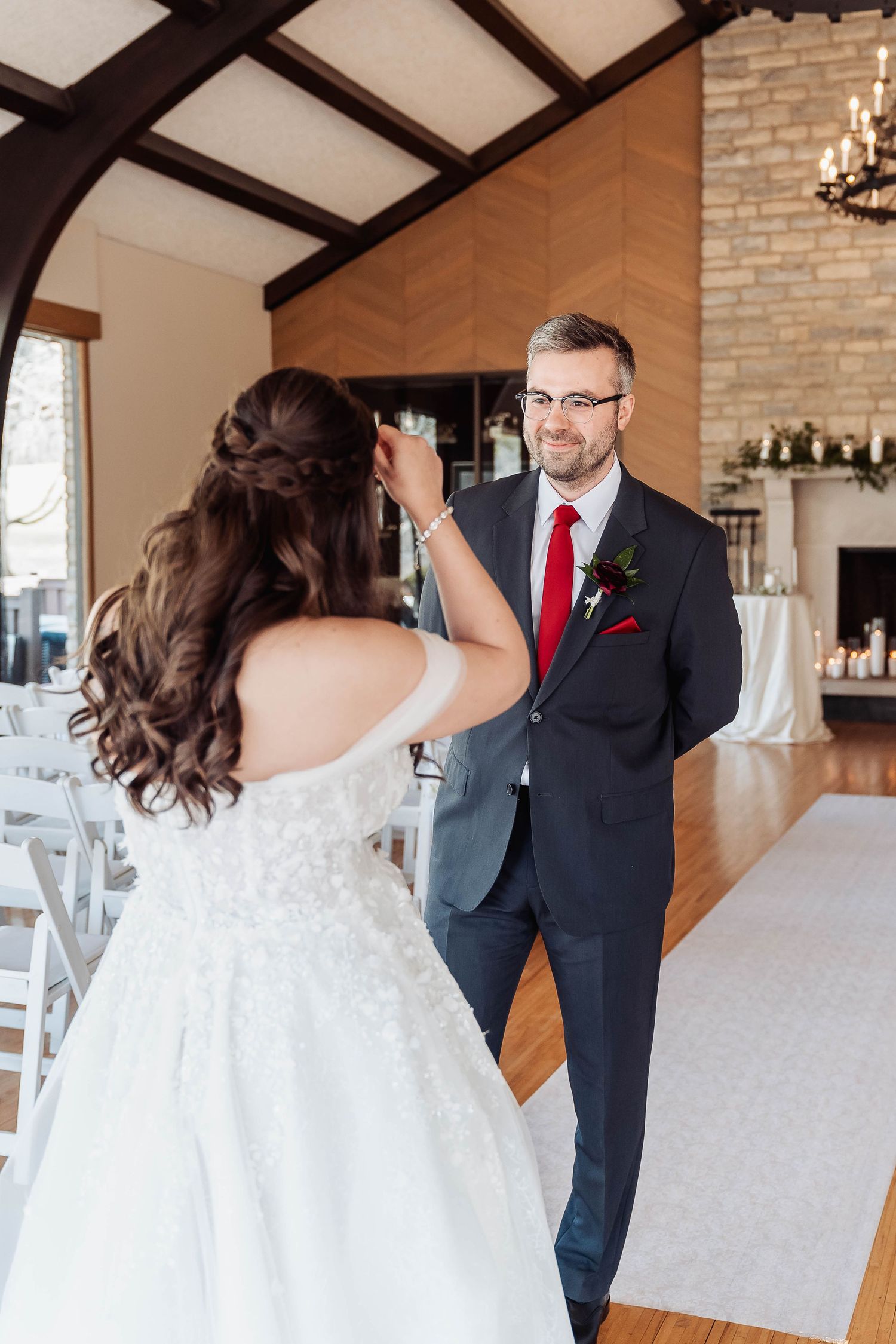 Bride and groom share a first look moment inside an elegant wedding venue with stone fireplace.