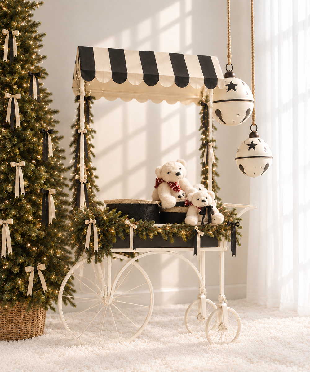 A festive Christmas cart with striped canopy holds teddy bears, beside decorated trees and a hanging bell ornament.