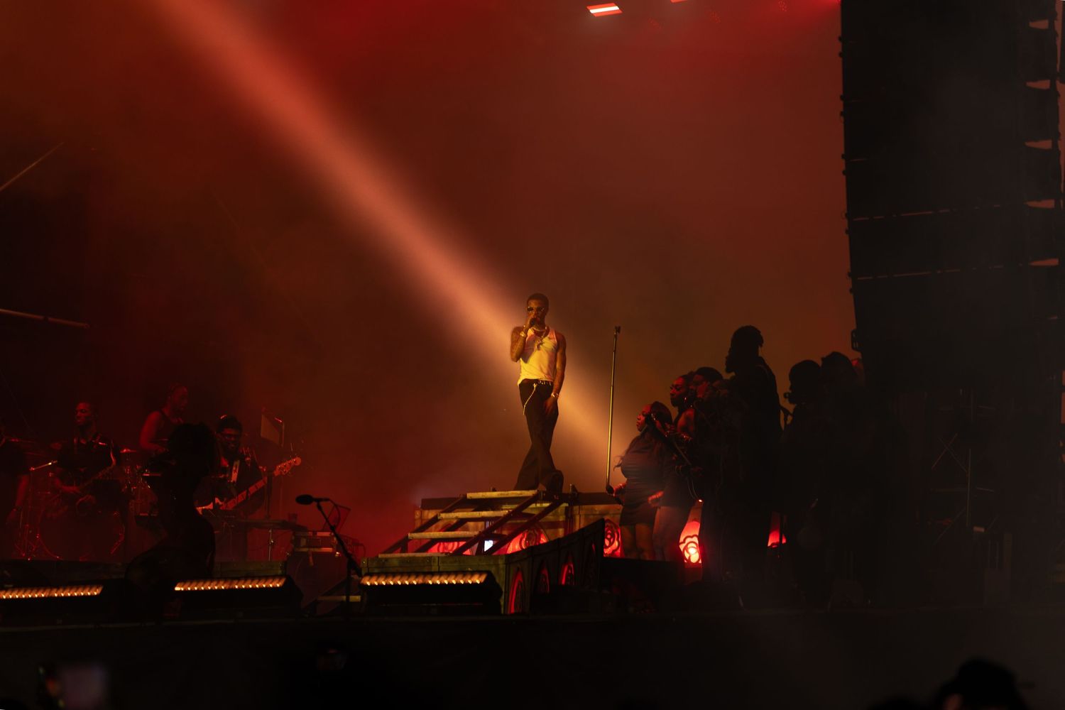 Performer on stage with red LED lights and dramatic fog effects under a bright spotlight at a nighttime concert.