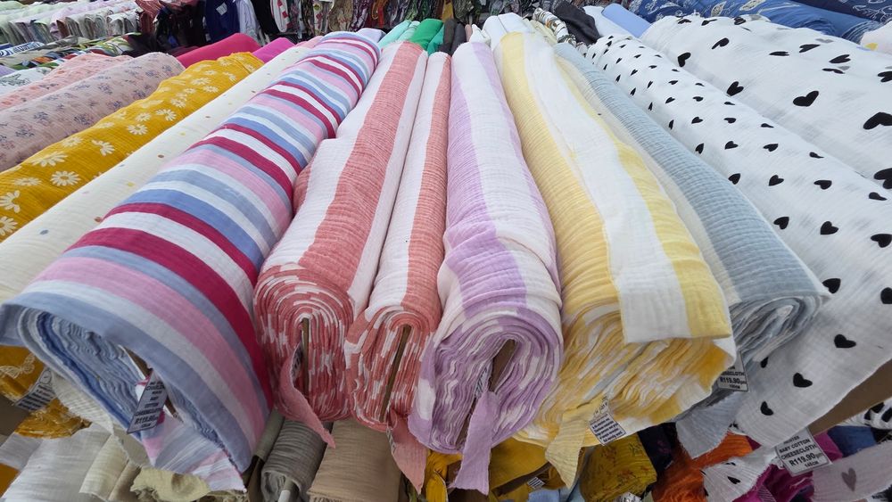 Colorful rolls of striped and patterned fabric bolts displayed at a textile market stall.