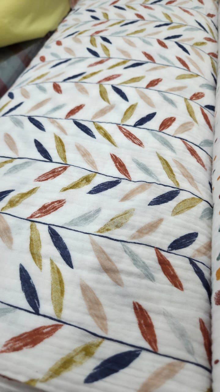 White quilted fabric with colorful leaf pattern in navy, rust, gold, and blue tones.