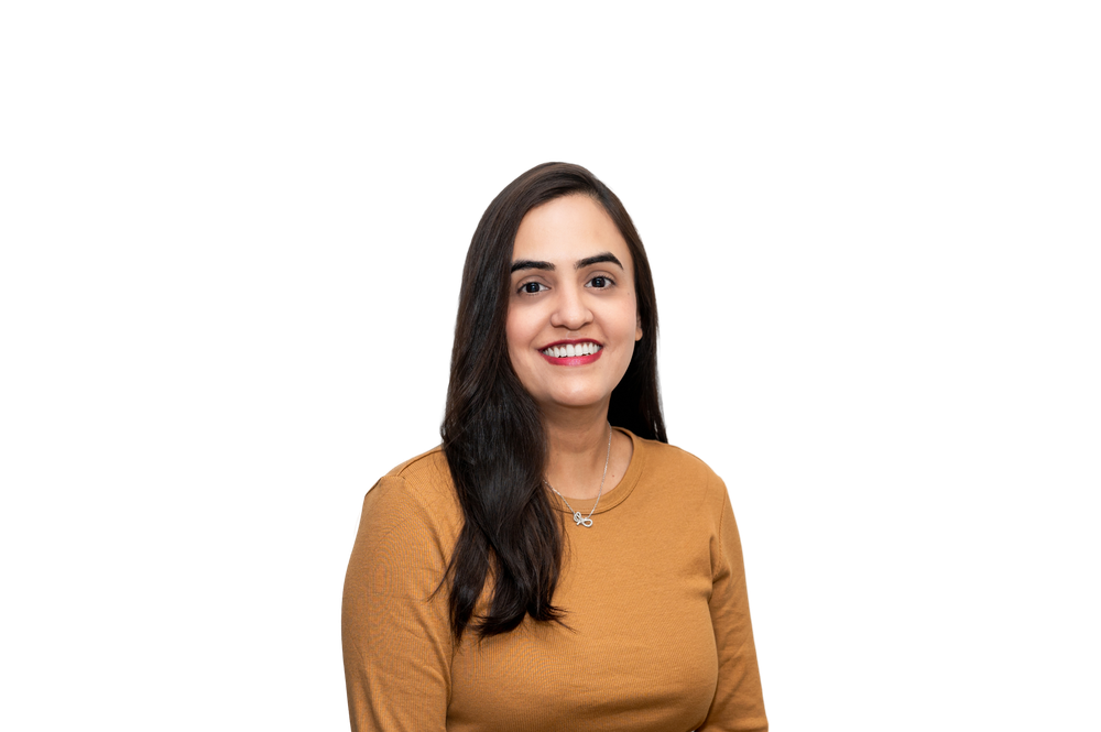 Professional headshot of a smiling woman with long dark hair wearing a mustard yellow top and delicate necklace.