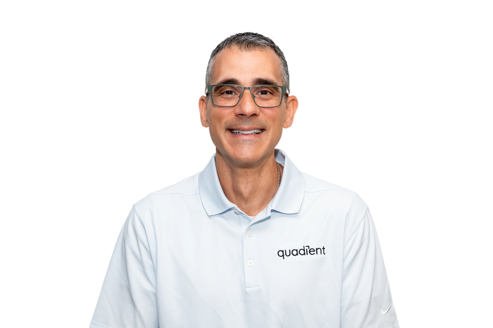 Smiling middle-aged man wearing glasses and a Quadient branded light blue polo shirt against a white background.