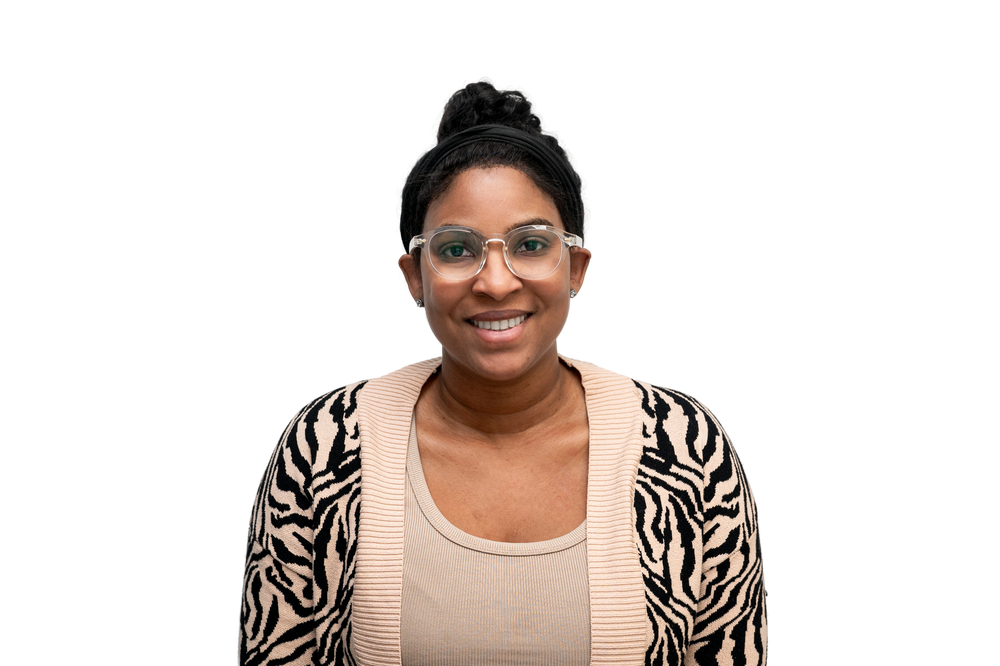 Smiling woman with glasses and zebra-print cardigan poses against white background.