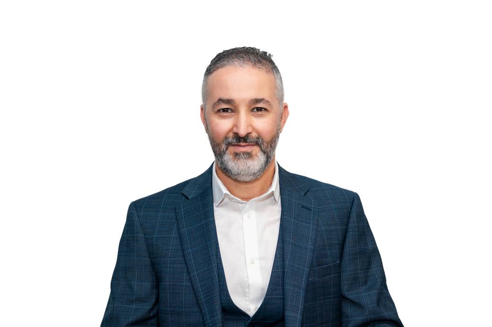 Professional man in navy blazer and white shirt smiling confidently against white background.
