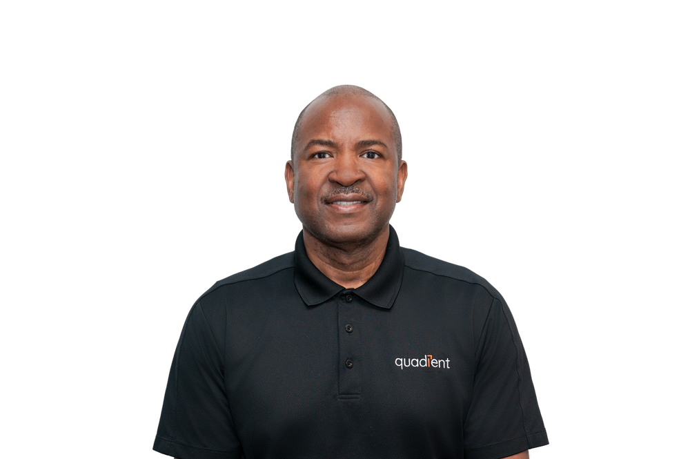 A smiling man wearing a black Quadient polo shirt poses confidently against a clean white background.