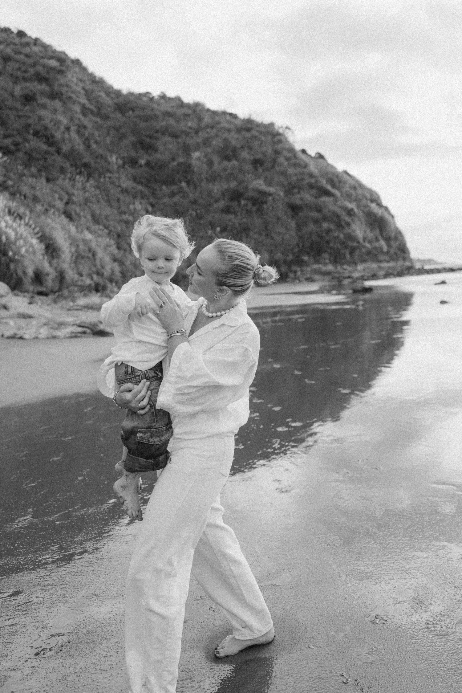 Mother walking hand in hand with her son during an outdoor family photography session in Raglan
