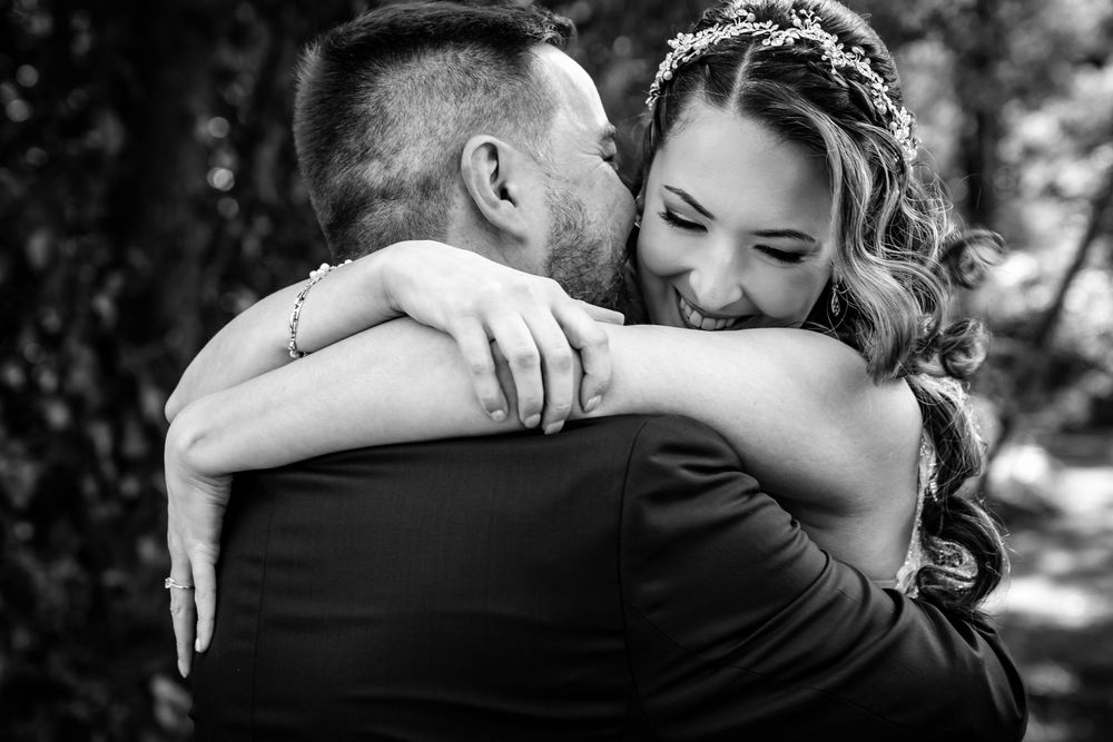 Black and white photo of a bride and groom sharing a tender embrace on their wedding day.