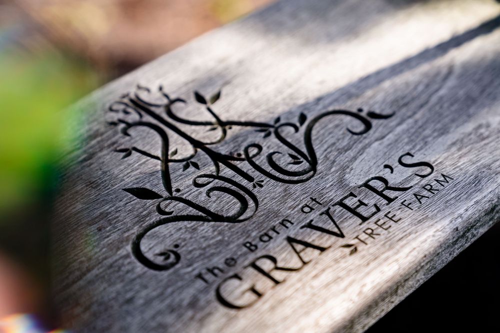 Close-up of engraved wooden sign reading The Born at Graver's Tree Farm with decorative script lettering.