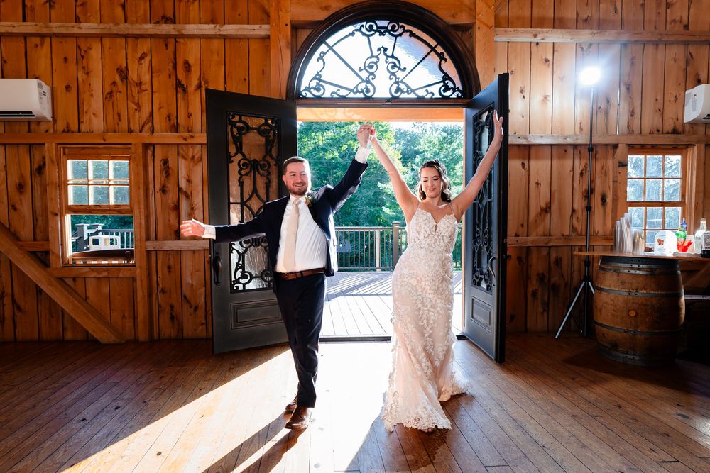 Bride and groom make grand entrance through ornate double doors of a rustic barn venue.
