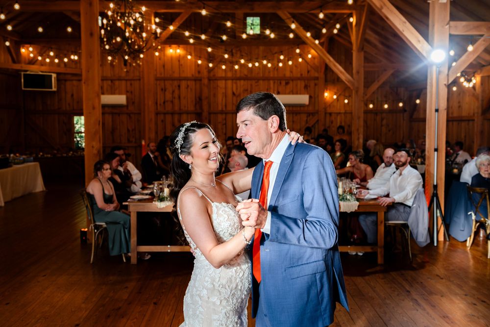 Couple shares intimate first dance in rustic barn reception venue with warm string lights.