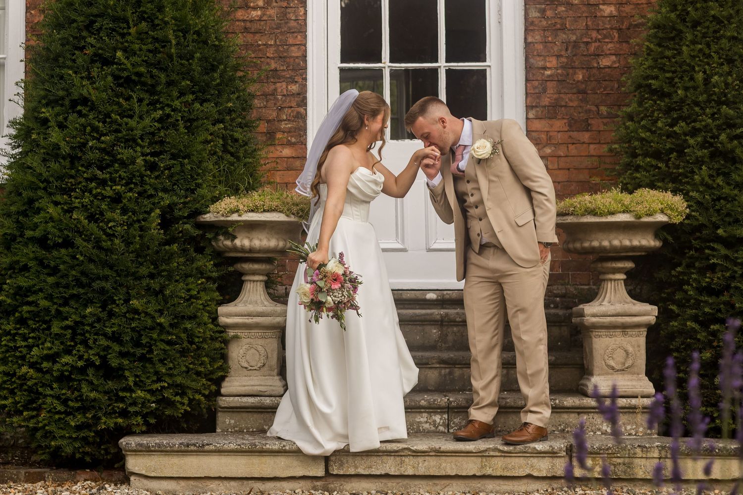 Wedding dress train flows dramatically against an ivy-covered brick wall background.