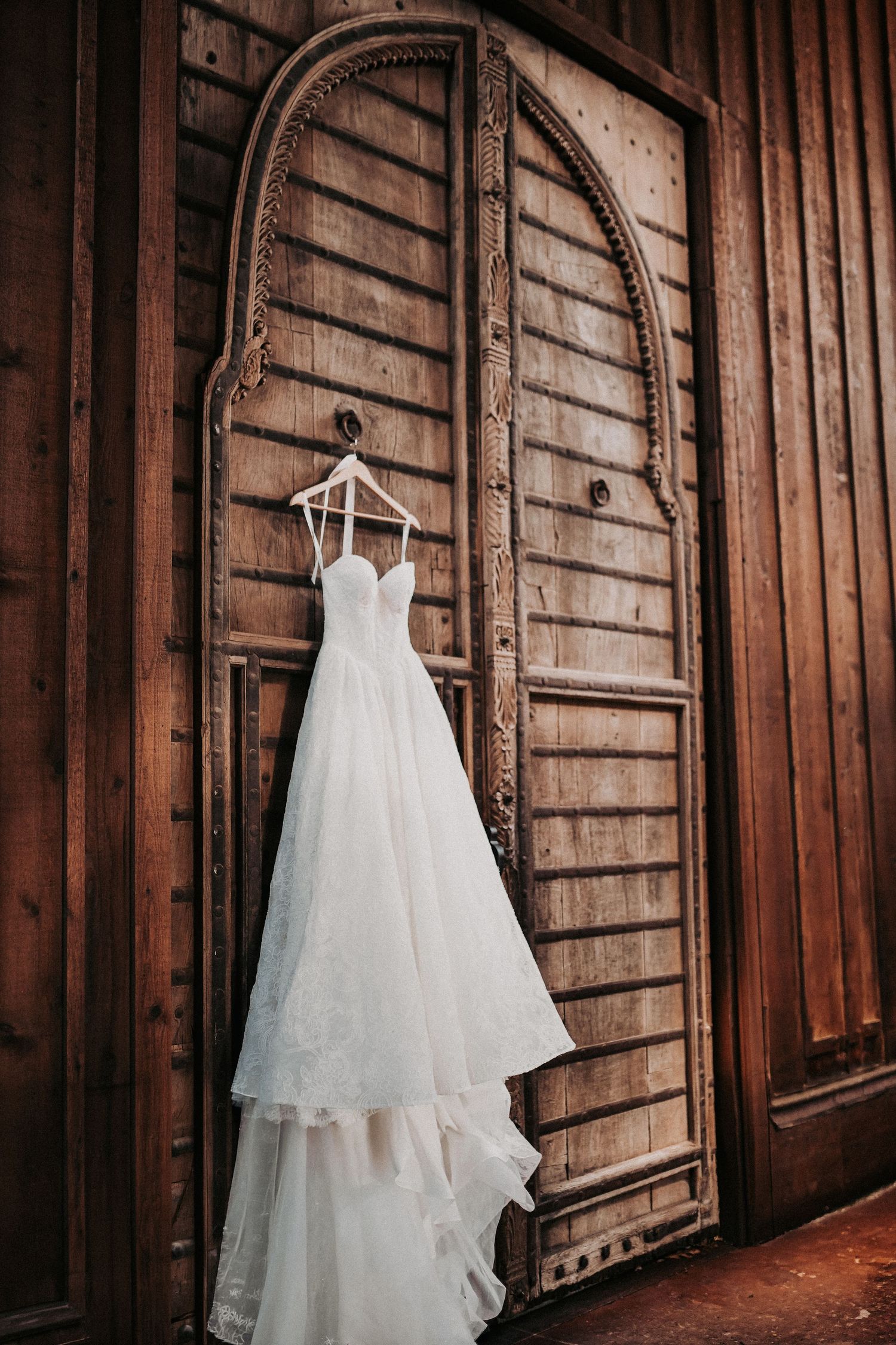 Vintage inspired lace bridal gown hanging on door before wedding ceremony