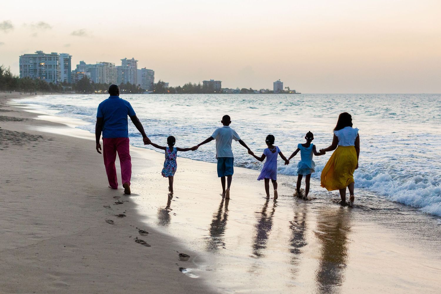 Family portrait. Mom, dad, and four kids holding hands and walking on the beach in Isla Verde, Carolina, Puerto Rico.