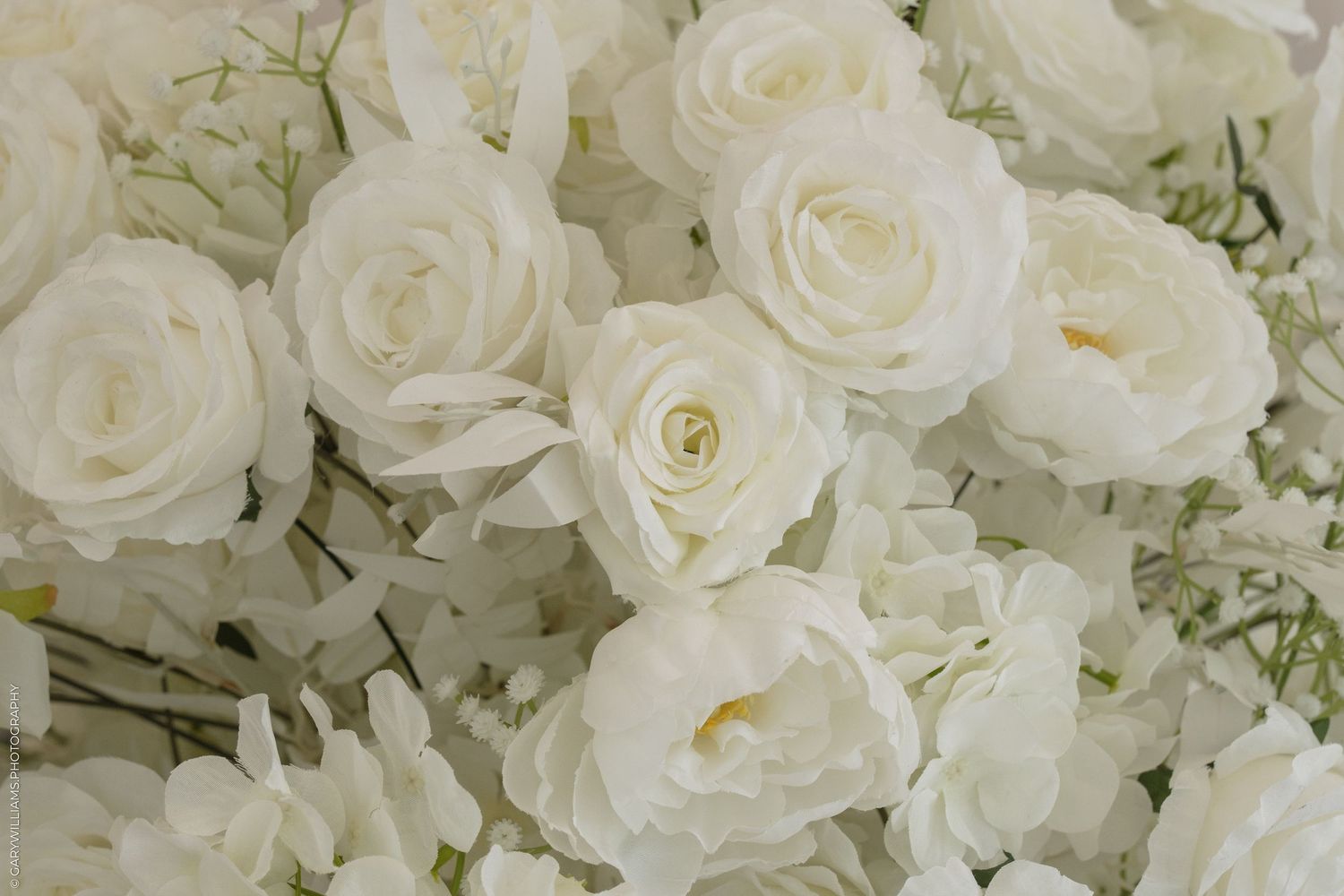 Close-up of elegant white roses and hydrangeas arranged in a lush floral display, perfect for weddings or events.