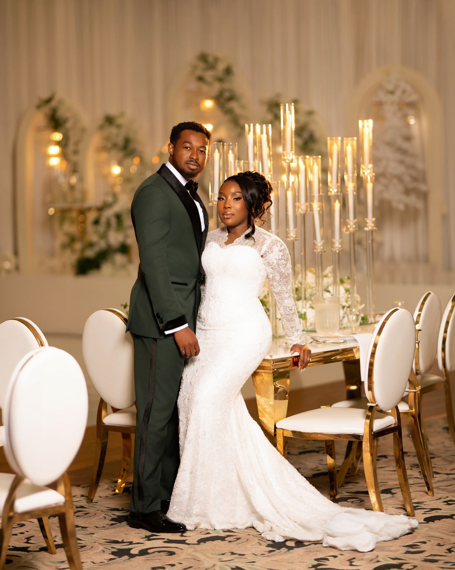 Elegant bride and groom posing at a gold wedding reception table with tall candelabras and white floral arrangements.