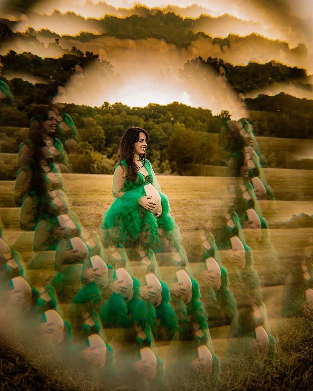 Pregnant woman in green tulle gown poses in golden field with dreamy multiple exposure effect and dramatic cloudy sky in Oak Ridge, TN.