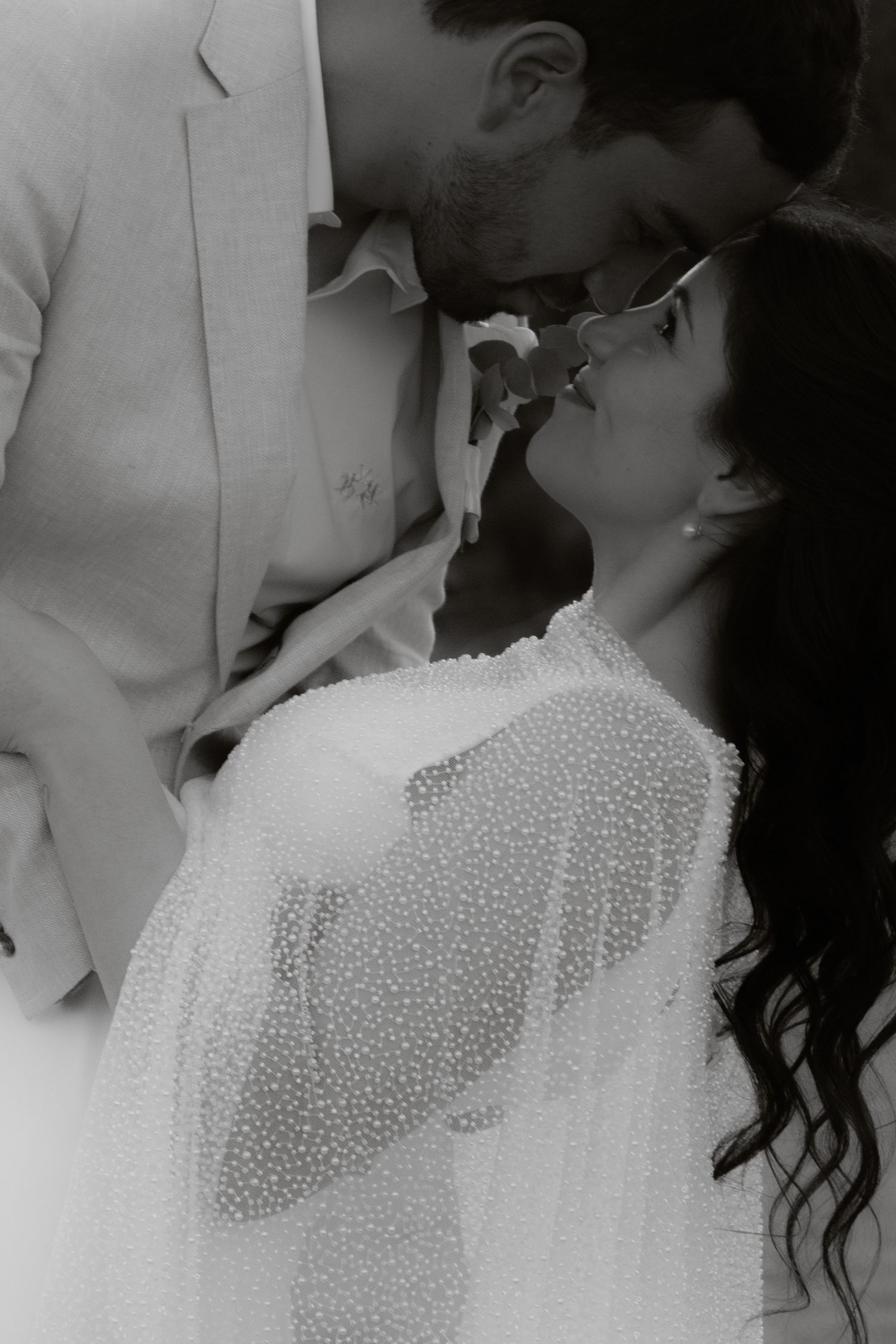 Black and white close-up of bride and groom sharing an intimate romantic moment.