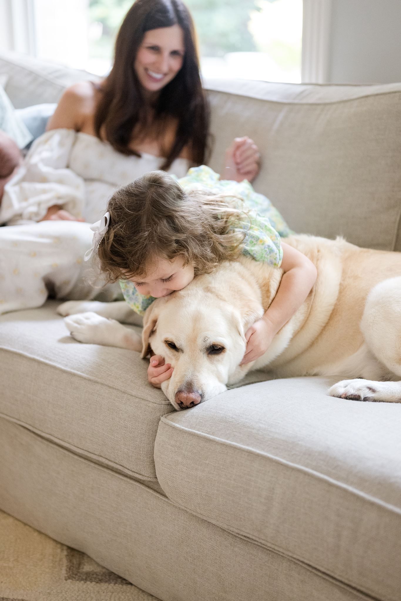Toddler cuddling their dog during family photos at home