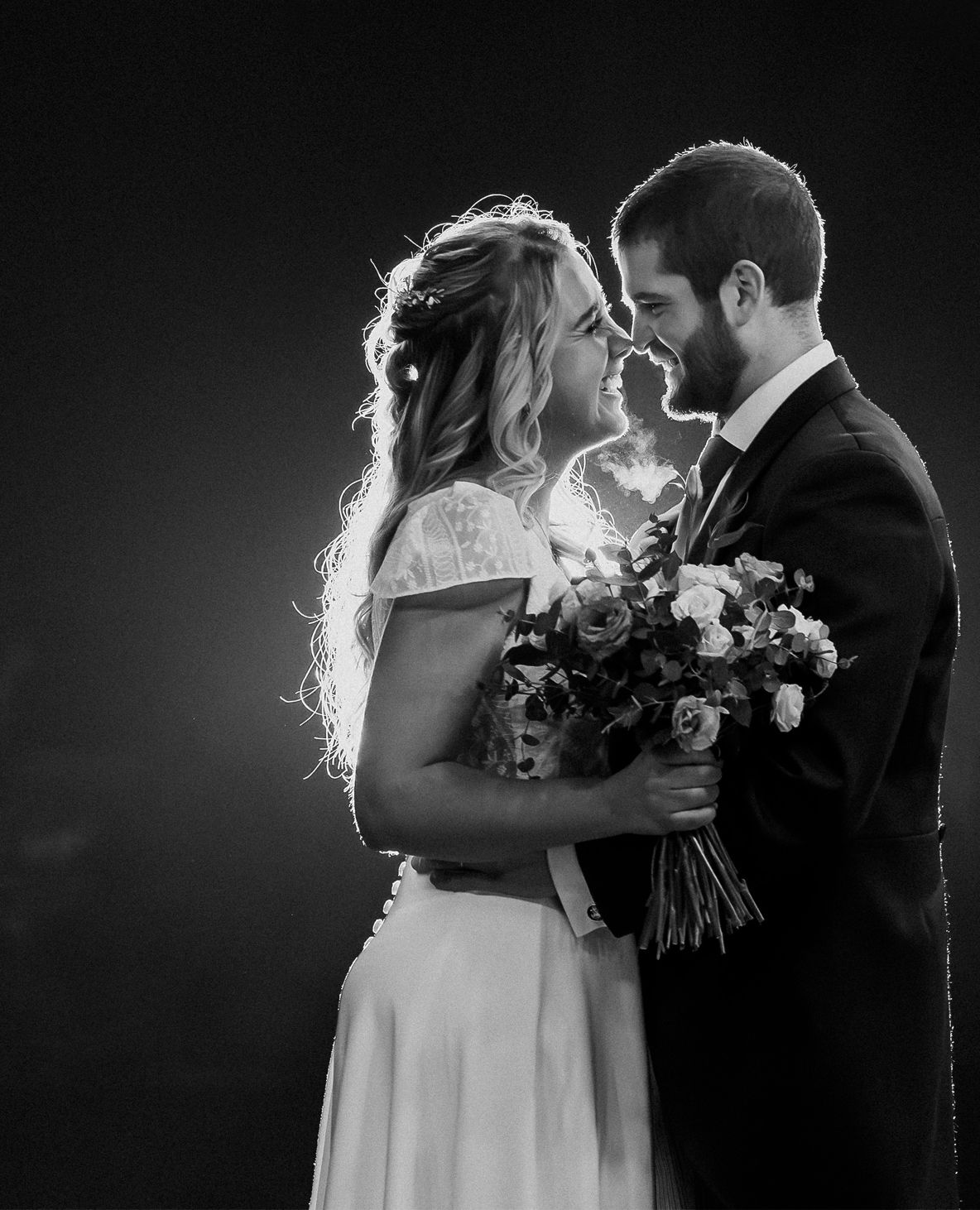 Black and white romantic portrait of bride and groom touching foreheads.