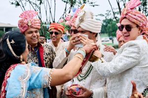Colorful Indian wedding ceremony with groom in white sherwani and turban surrounded by groomsmen in pink turbans.