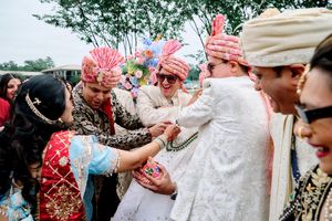 Indian wedding guests in colorful traditional attire celebrating with the groom during a festive ceremony.