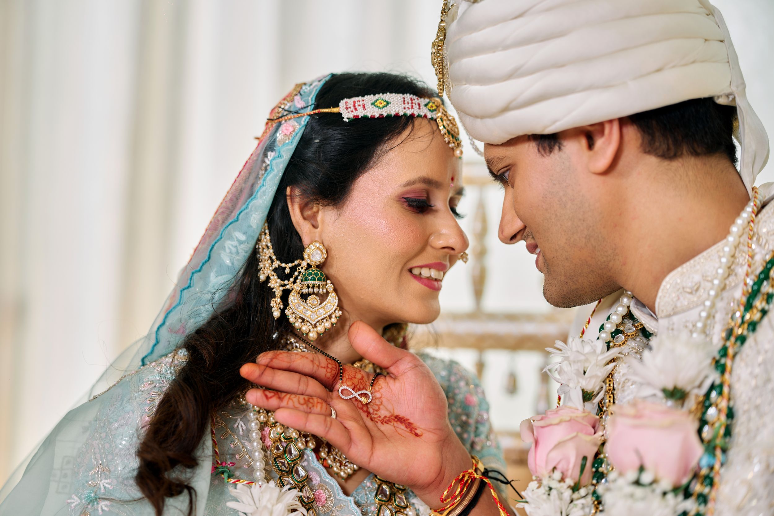 Indian bride and groom in light blue and white wedding attire sharing an intimate moment at ceremony.