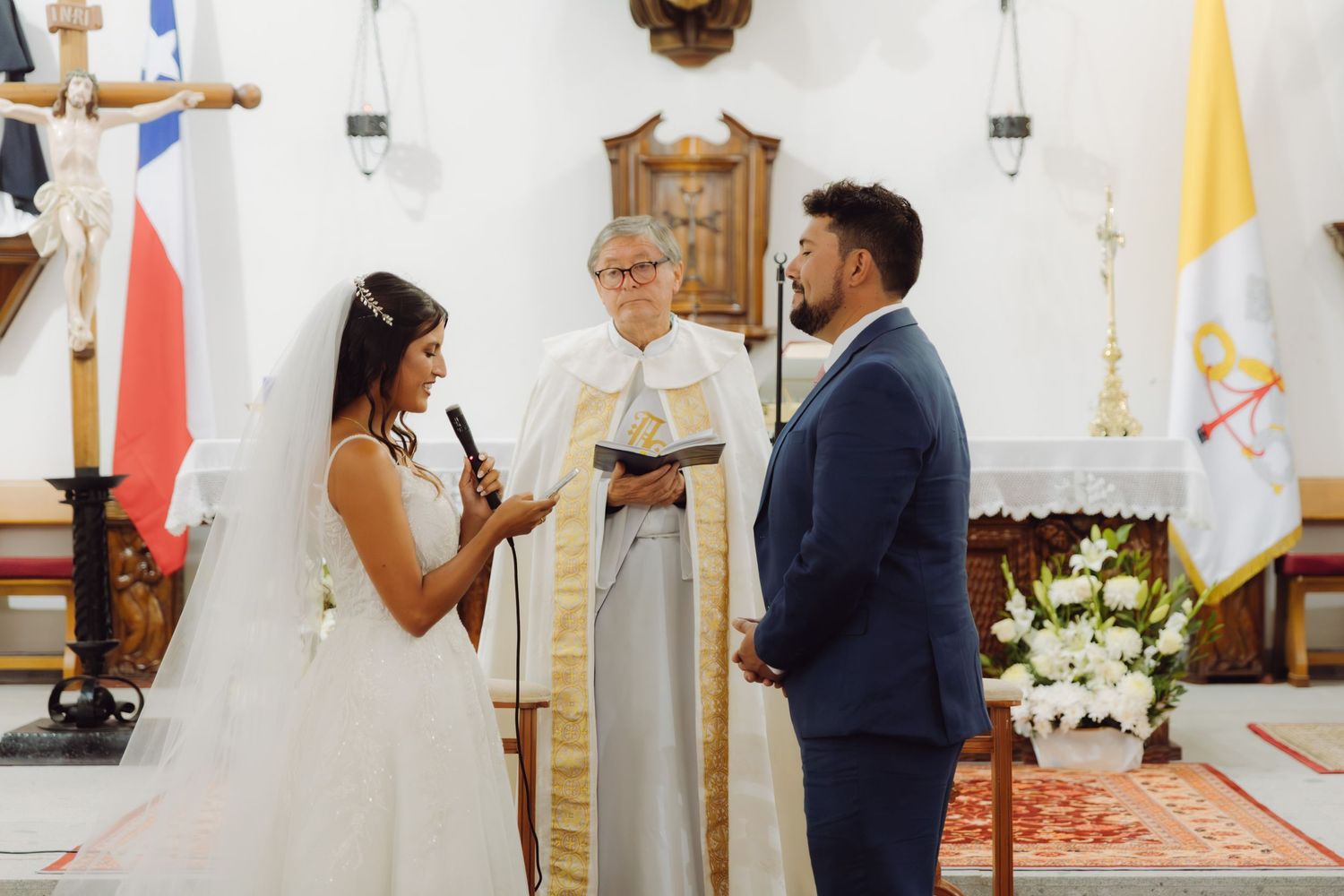 Bride reads vows to groom before priest at a Catholic church wedding ceremony.