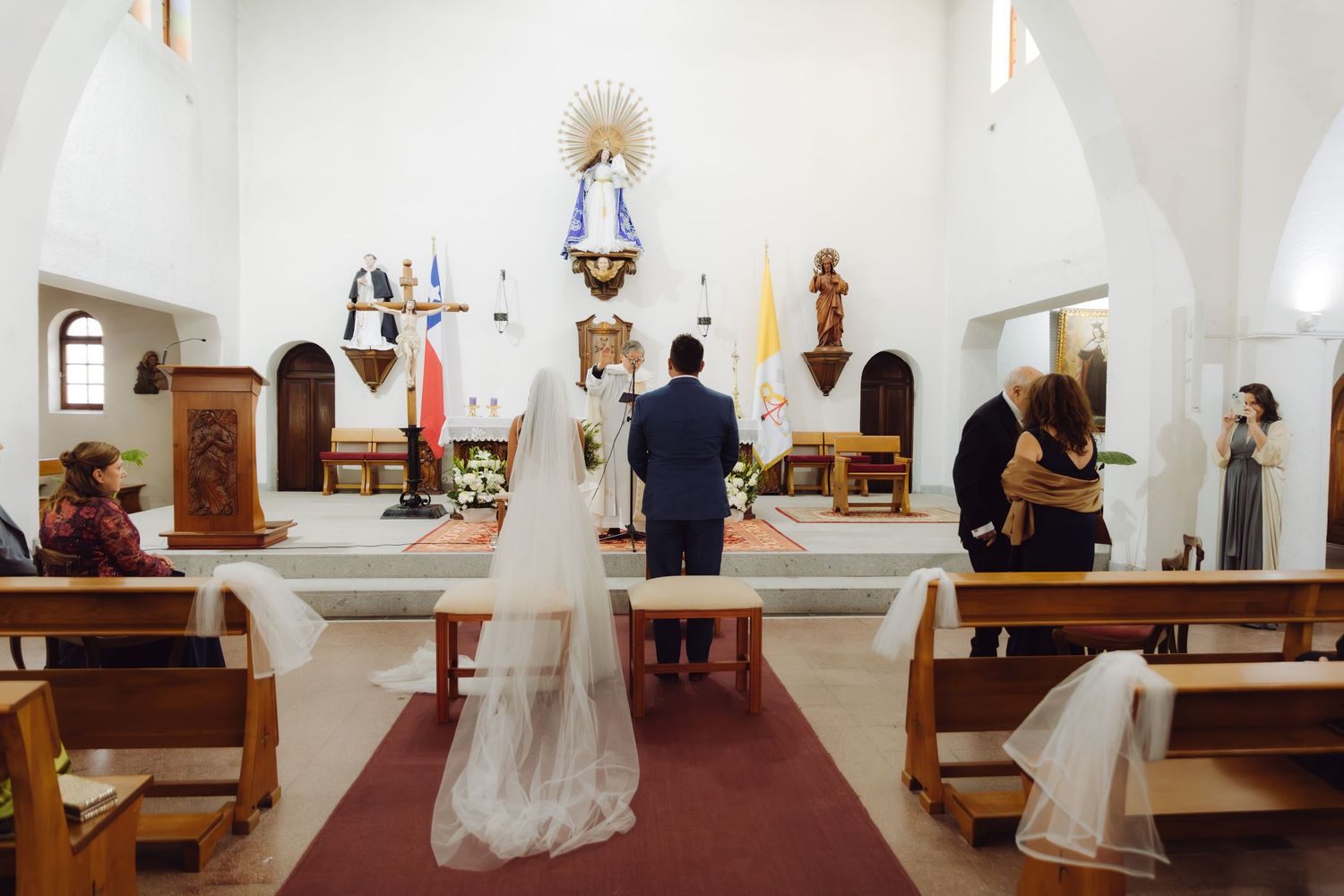 Bride and groom kneel before the altar during a traditional Catholic church wedding.