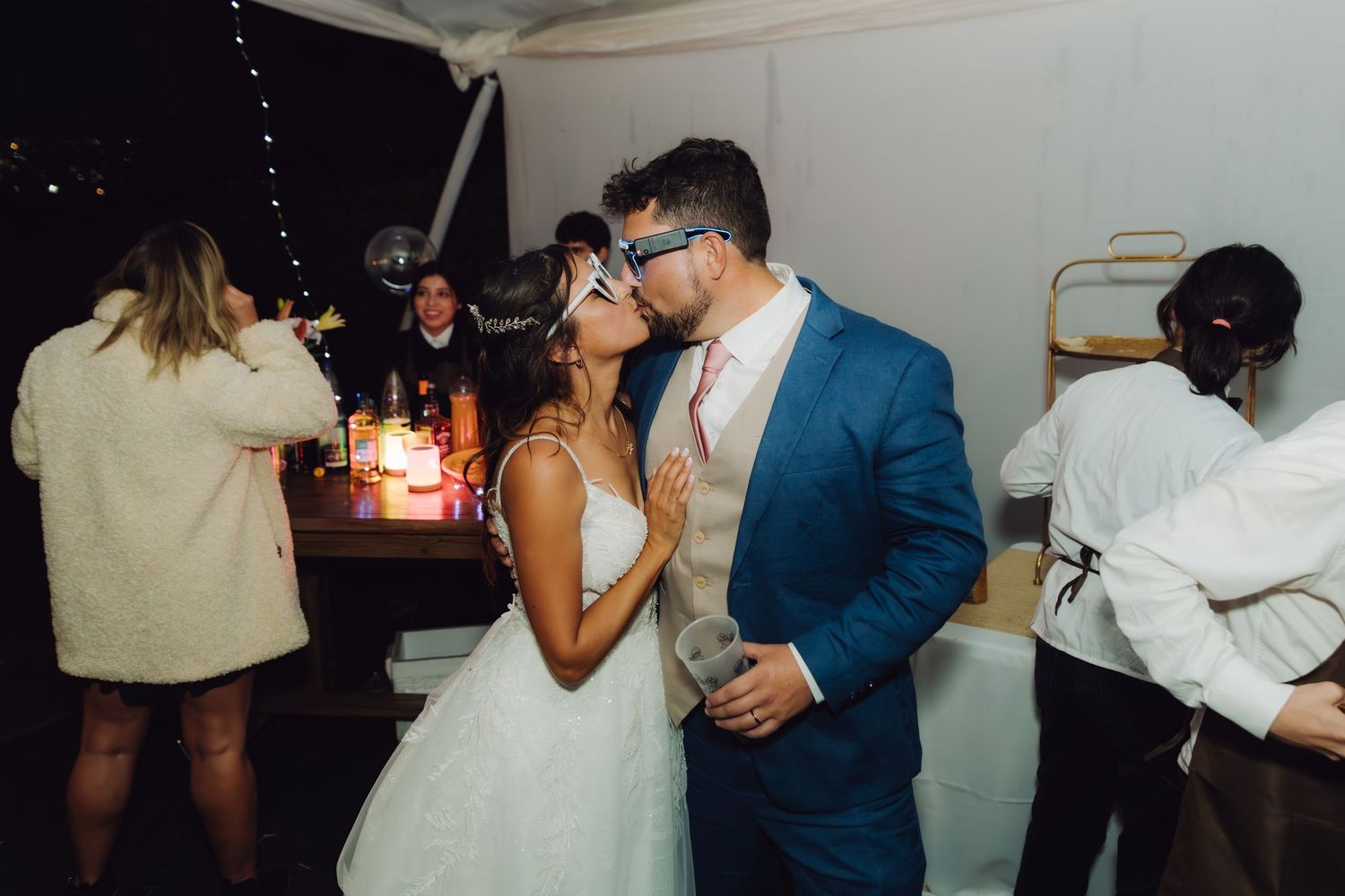 Bride and groom sharing a romantic kiss at their evening wedding reception.
