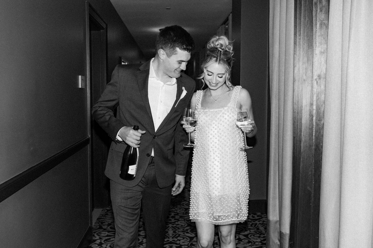 Bride and groom share first dance on black and white checkered floor under disco balls at elegant wedding venue.